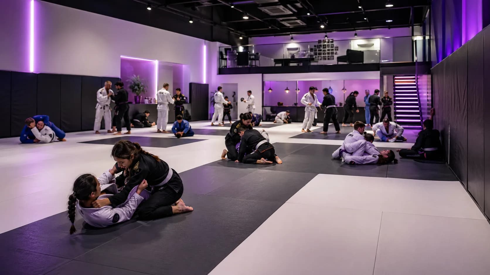 Modern martial arts gym with classes running on black and white mats